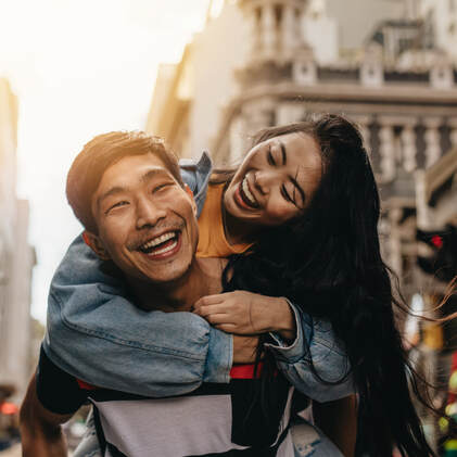 Man carrying woman on his back while both are laughing